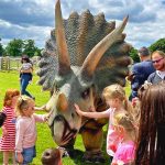 Children playing with life size model Triceratops