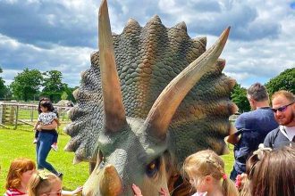 Children playing with life size model Triceratops