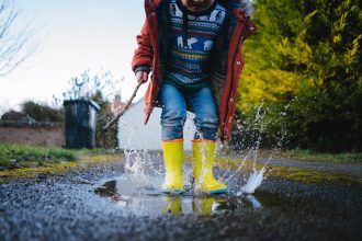 A picture of a young child enjoying jumping in muddy puddles.