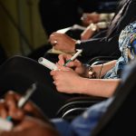 A row of people making notes at a business conference