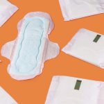 Period products (an unwrapped sanitary pad surrounded by wrapped sanitary pads