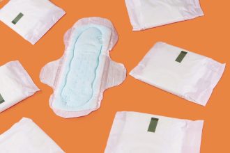 Period products (an unwrapped sanitary pad surrounded by wrapped sanitary pads