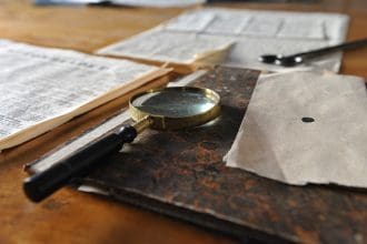 Magnifying glass on top of a file surrounded by sheets of paper