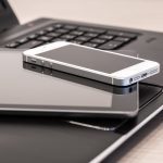 Pile of digital technology with a tablet and mobile phone on top of an open laptop