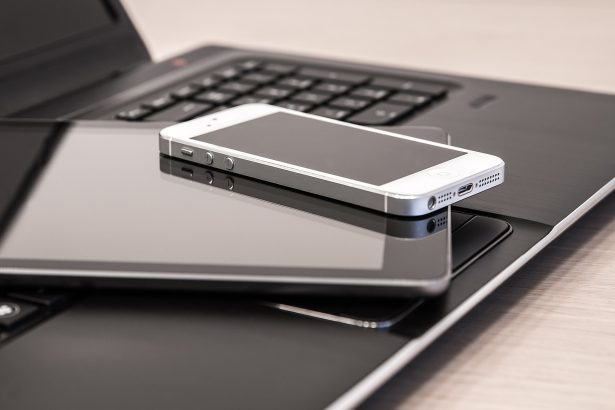 Pile of digital technology with a tablet and mobile phone on top of an open laptop