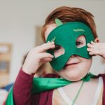 Young child in fancy dress outfit with green mask