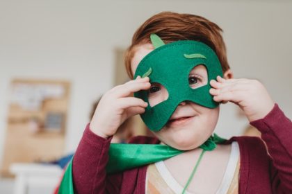 Young child in fancy dress outfit with green mask