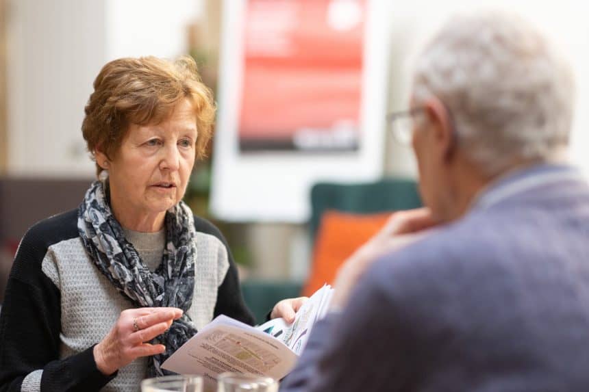 Two older adults sitting across from each other at a table having a conversation